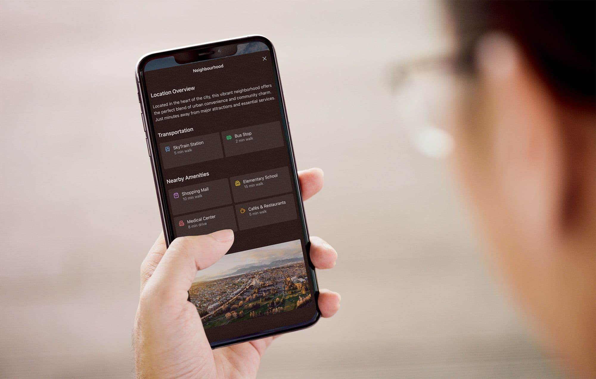 Hand holding a smartphone showing a neighbourhood guide with transit and nearby amenity walking times