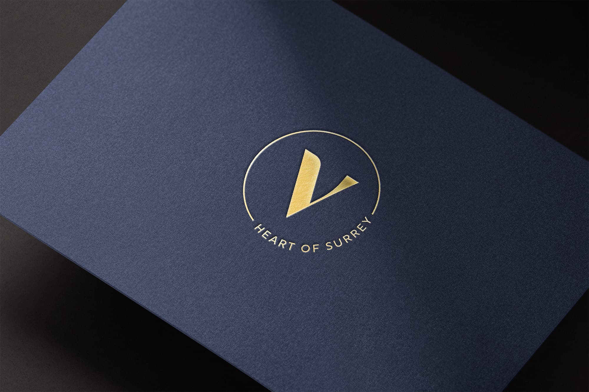 Gold foil Vara 'V' submark with 'Heart of Surrey' on a navy textured card