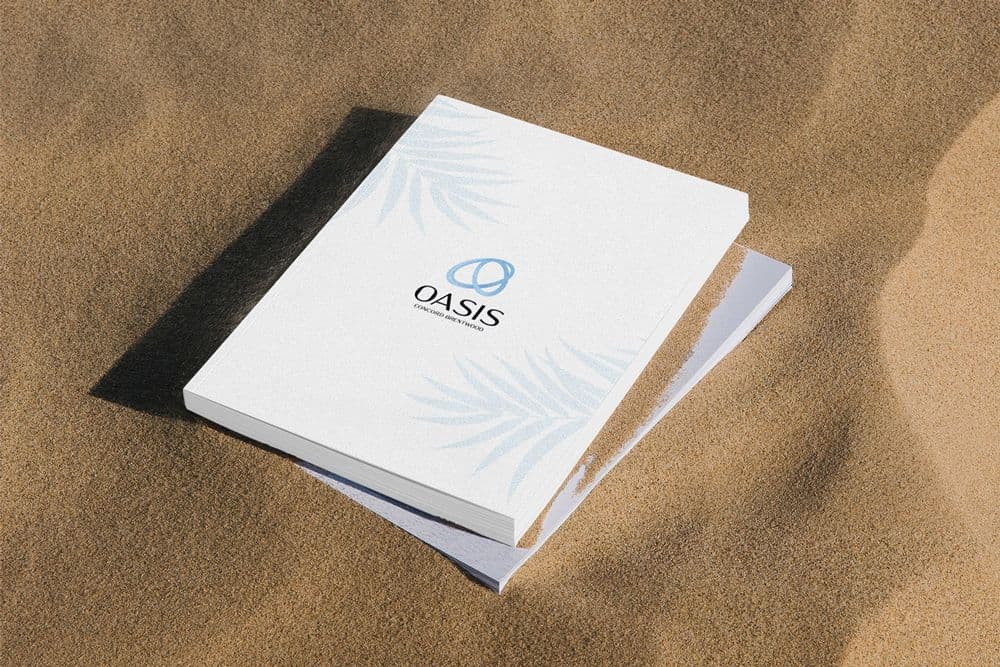 Oasis at Concord Brentwood brochure with a blue logo and palm leaf pattern resting on sand